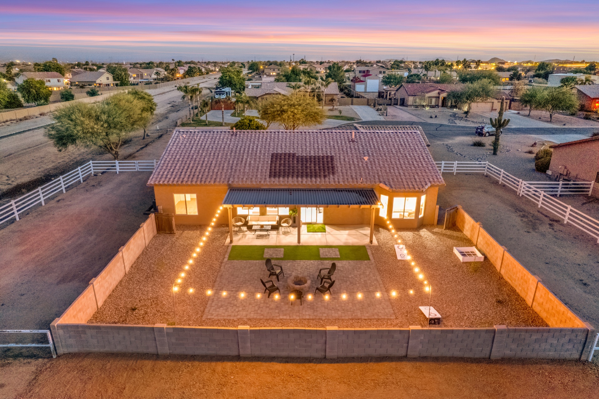 Drone aerial view of property with string lights at twilight
