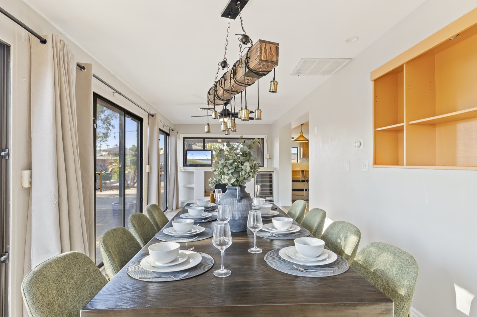 Dining table styled with place settings under a beam light fixture
