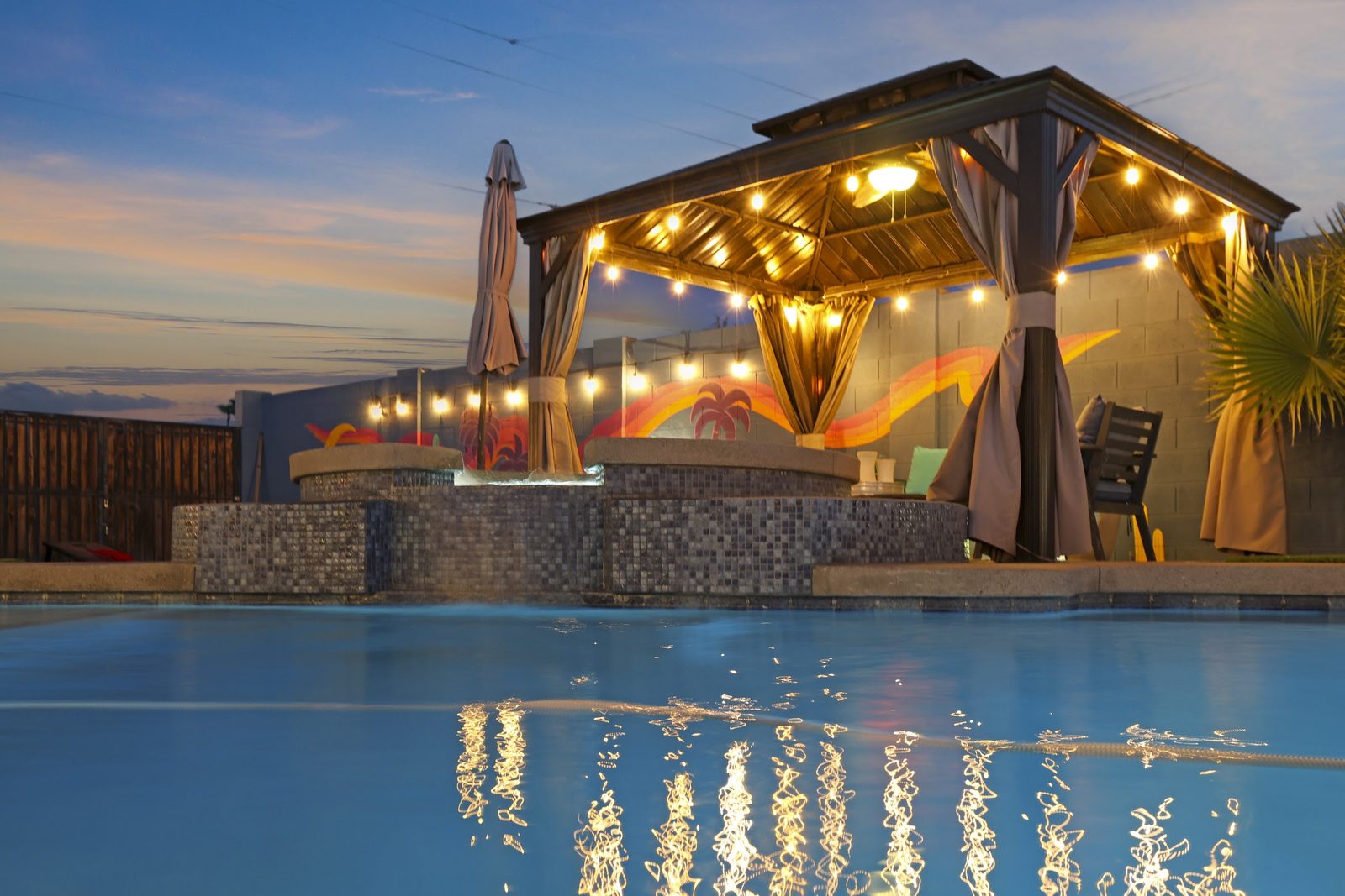 Backyard of a recent Scottsdale Airbnb shoot at twilight: a lit ramada and pool under string lights. Booked Visual
