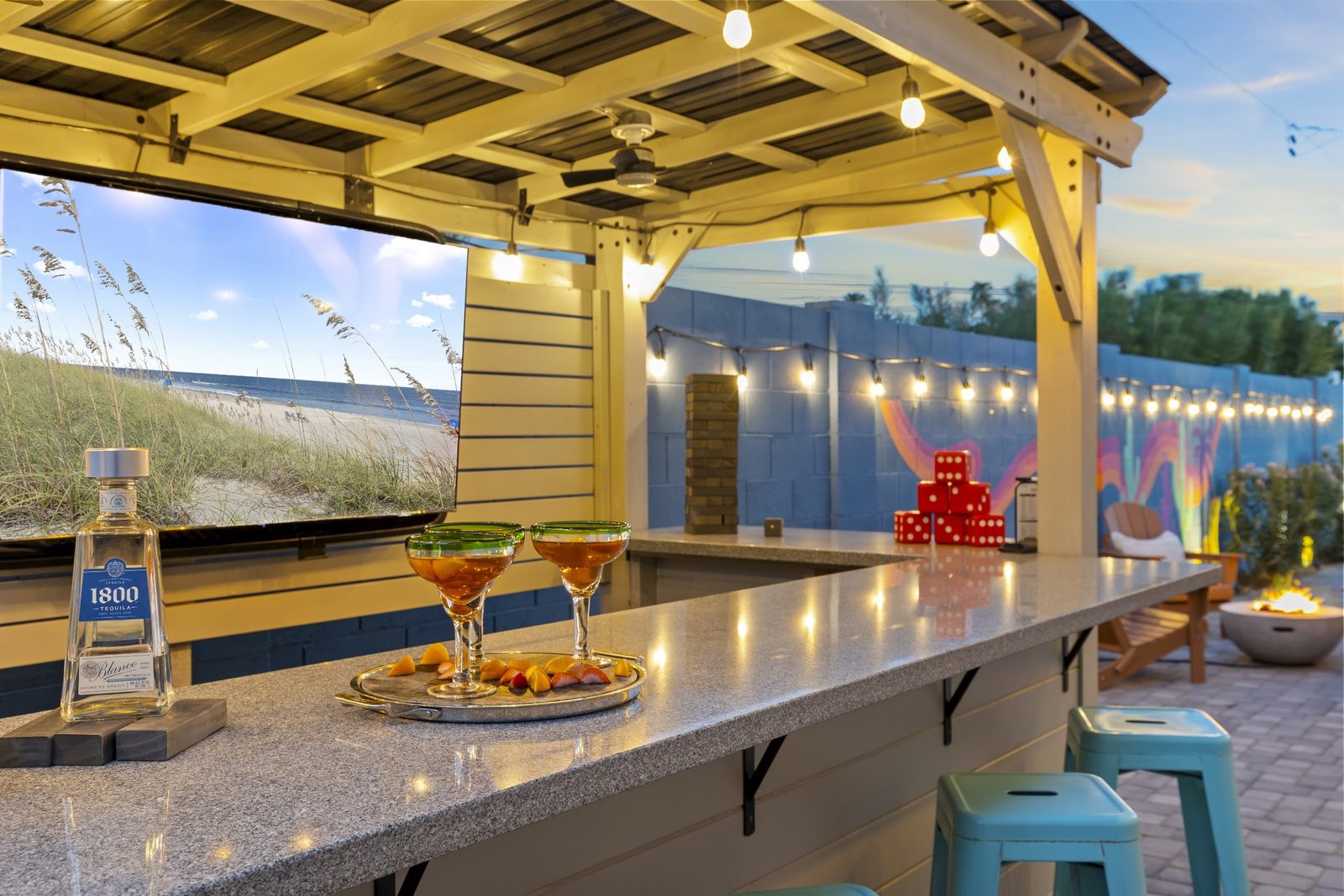 Styled outdoor bar with drinks poured and fruit plated, string lights on, at a Scottsdale Airbnb