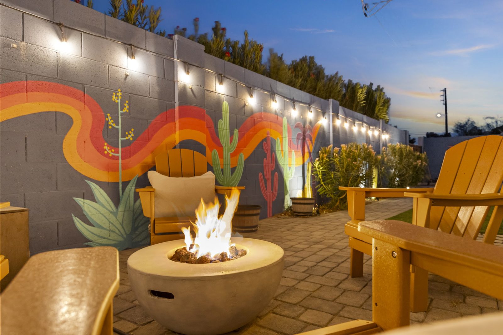 Fire pit lit with chairs and cushions arranged around it at twilight, Scottsdale short-term rental
