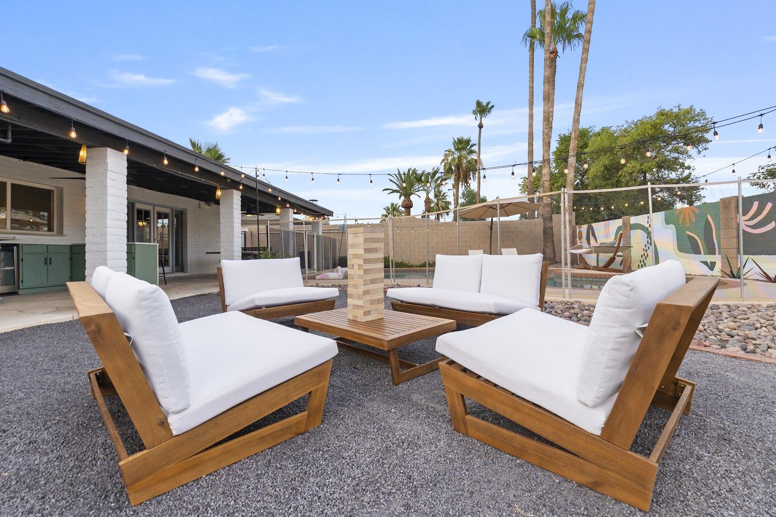 Daytime backyard of a recent Tempe Airbnb shoot: lounge seating, string lights, and a pool. Booked Visual