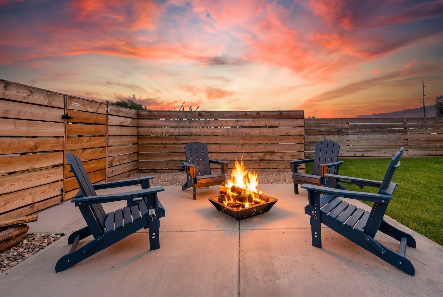 Backyard fire pit ringed by Adirondack chairs under a vivid sunset