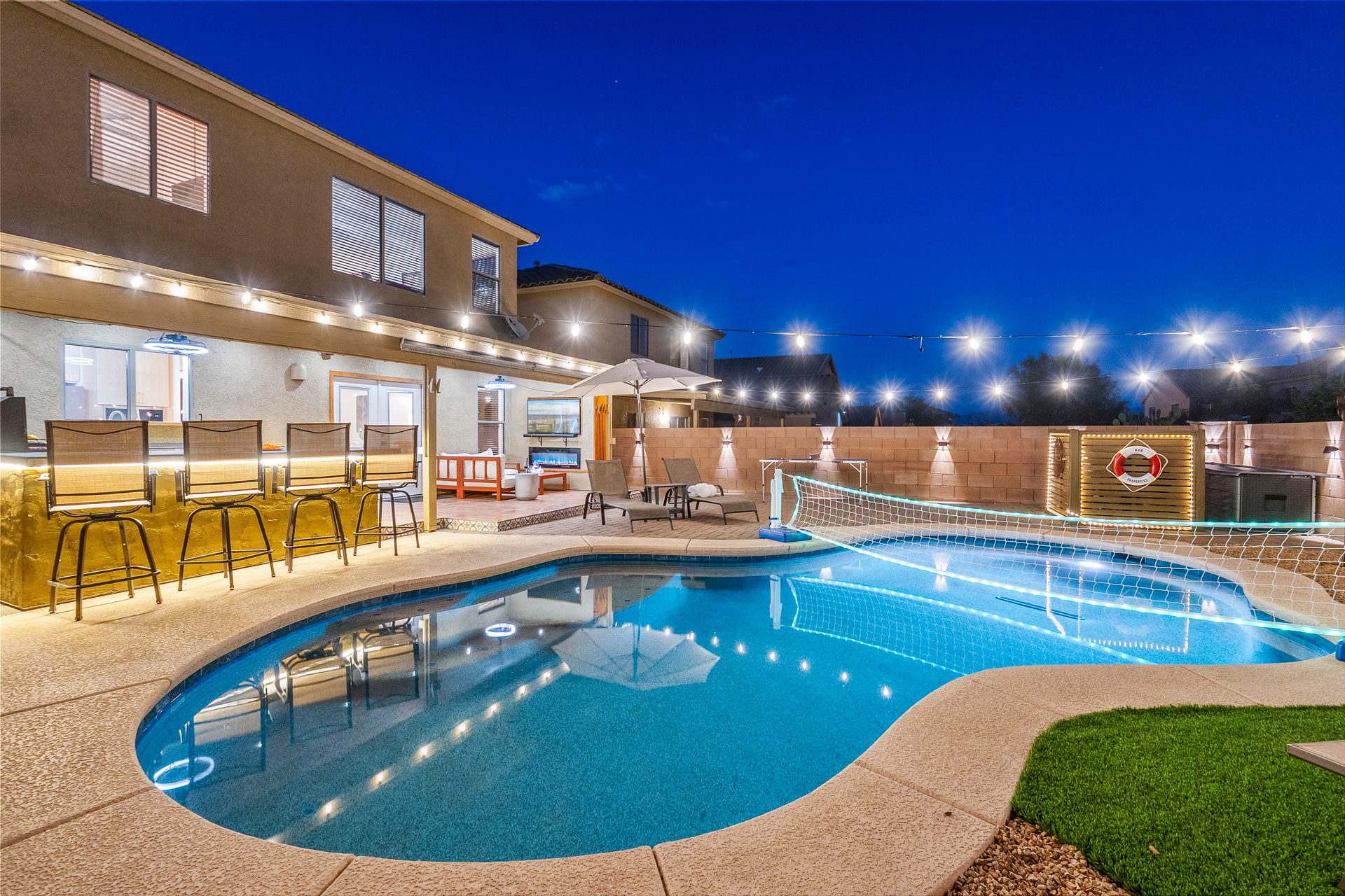 Lit pool, hot tub and covered patio at dusk at an Arizona rental
