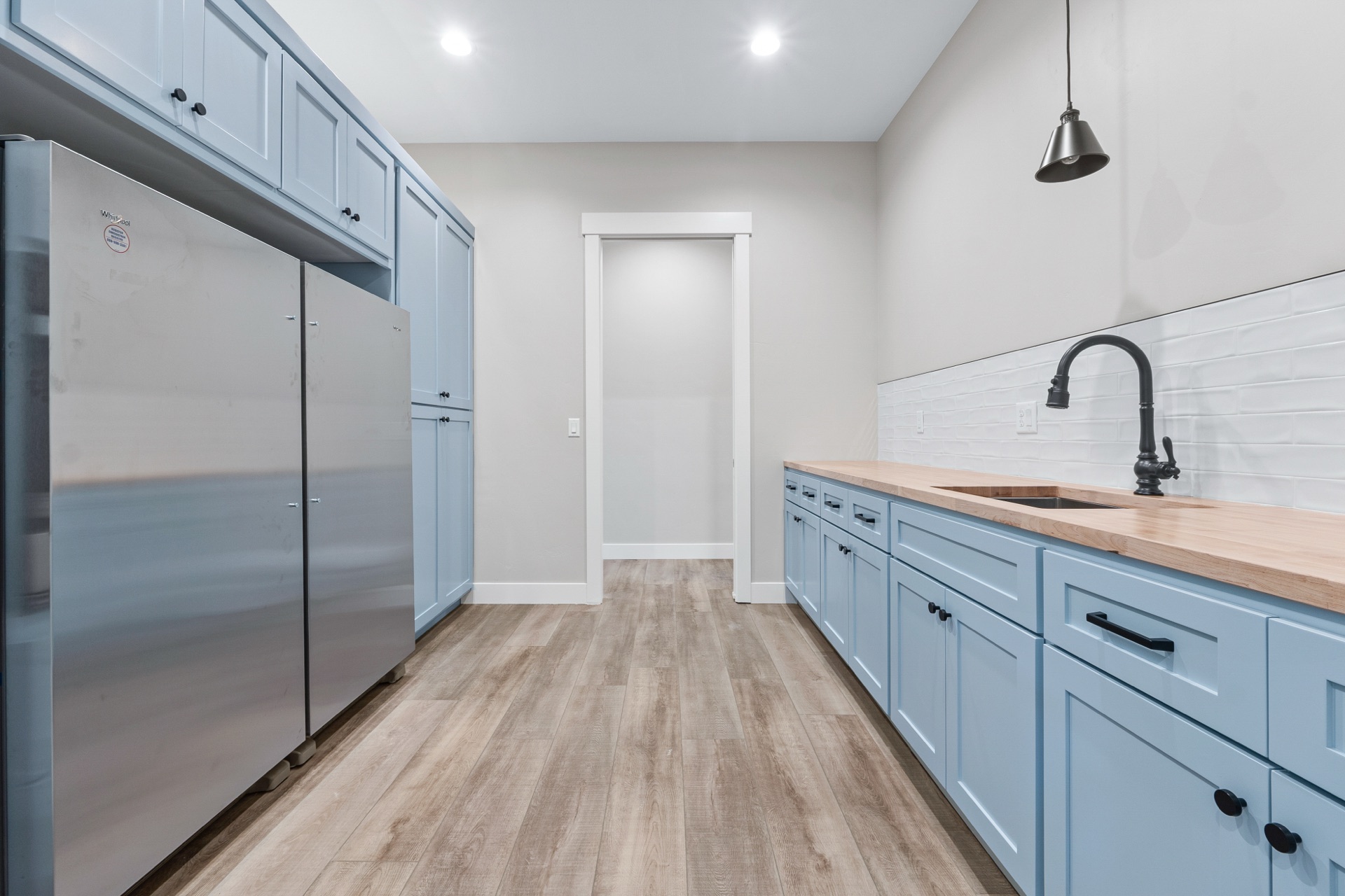 Blue butler pantry with stainless fridge and wood countertops